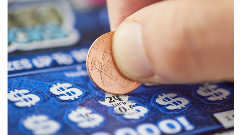 A close-up of a hand scratching a lottery ticket