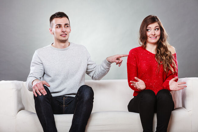 Shy woman and man sitting on sofa. First date.