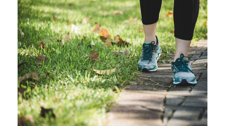 asian woman running in a park, closeup on the shoes