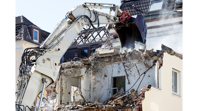 Excavator demolishing a house