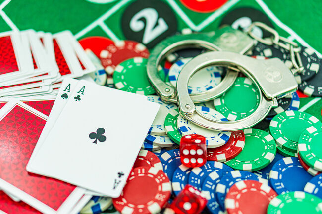 Handcuffs and a gun on a poker table - casino crime concept, underground casinos. illegal games, gambling concept. set of playing cards with dices, money and chips, on table. Casino concept, games.