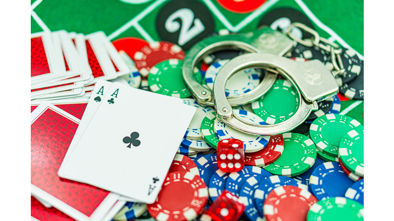 Handcuffs and a gun on a poker table - casino crime concept, underground casinos. illegal games, gambling concept. set of playing cards with dices, money and chips, on table. Casino concept, games.