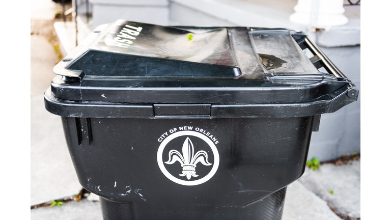Closeup of outdoor city trash can or rubbish garbage bin in Louisiana city with fleur-de-lis sign symbol outside