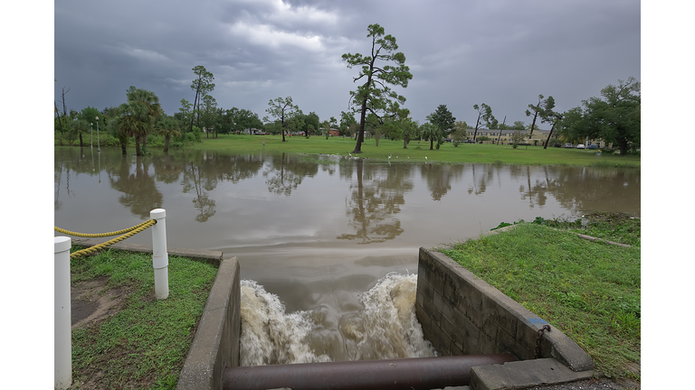 Floodwaters rush through a drain culvert, carrying fresh rainwater to the saltwater bay, creating a dynamic interplay of currents.