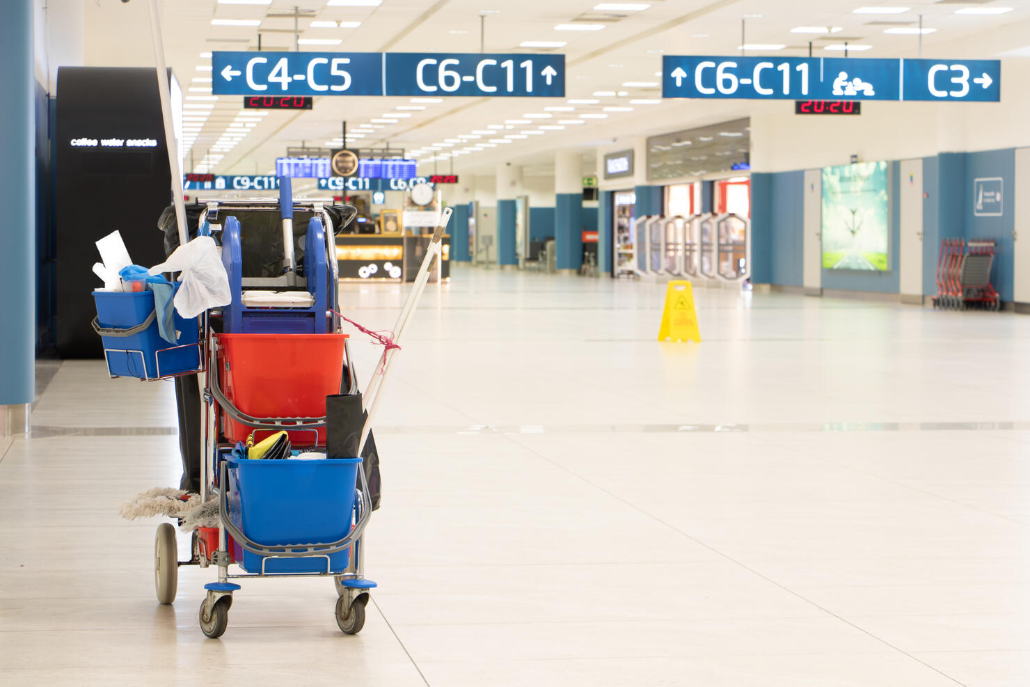 A service trolley with cleaning supplies in an empty airport terminal.