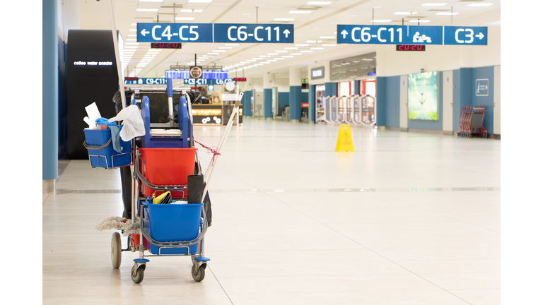 A service trolley with cleaning supplies in an empty airport terminal.
