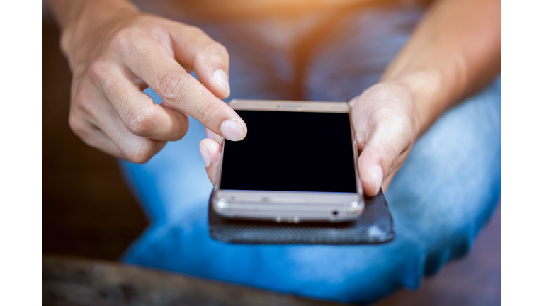 Close up of a woman hand using a smart phone on a desk at home