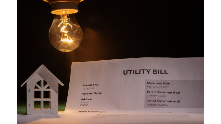 Utility bill and a house with a burning lightbulb, financial statement with cost breakdown, utility charges for electric power and heat, monthly budget planning