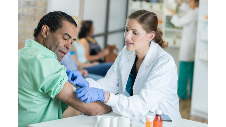 Caring healthcare professional places bandage on man's arm