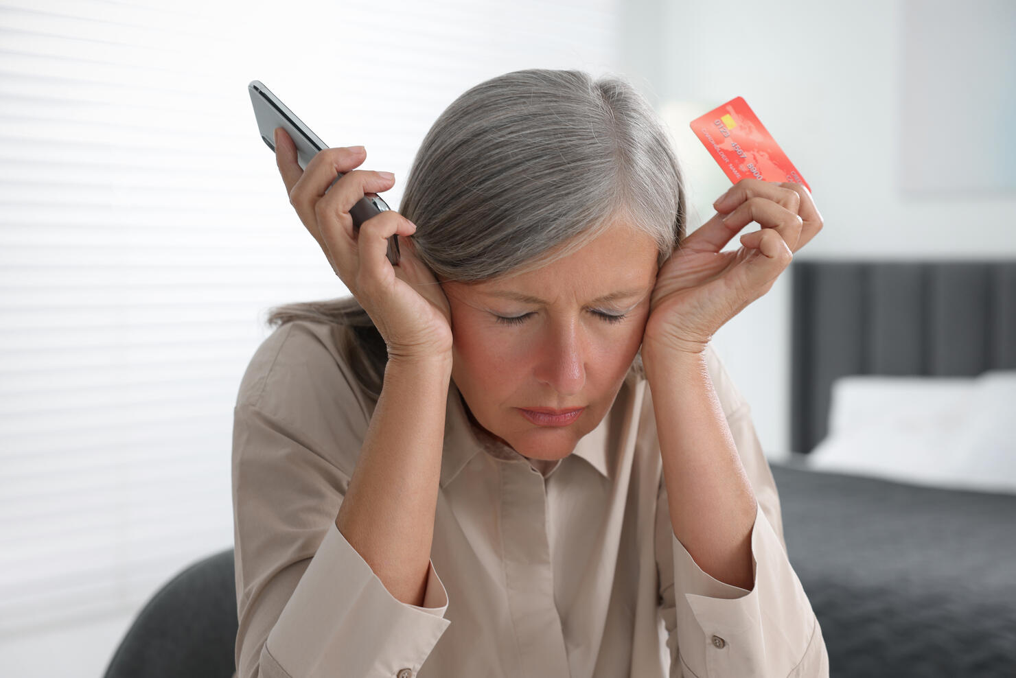Scammed woman with credit card and smartphone indoors. Be careful - fraud