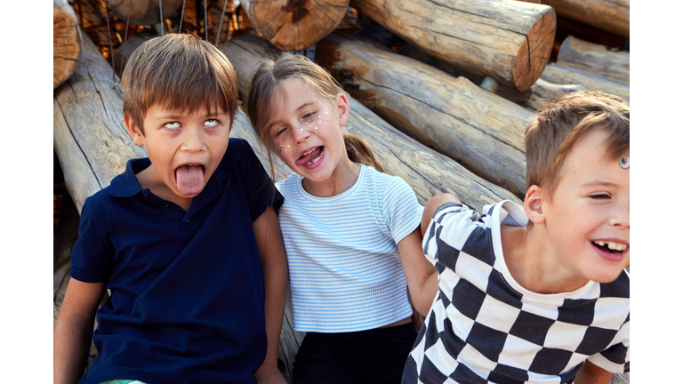 Children playing and having fun, making silly faces outdoors in the sunshine with friends and siblings