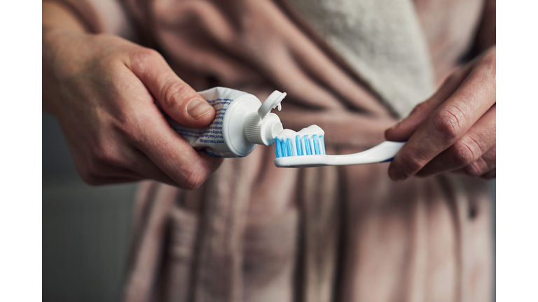 Woman putting toothpaste on a toothbrush