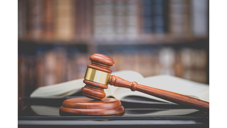 Legal office of lawyers, justice and law concept : Judge's gavel or hammer and base used by a judge person on a desk in a courtroom with blurred books and a bookshelf or bookcase in the background.