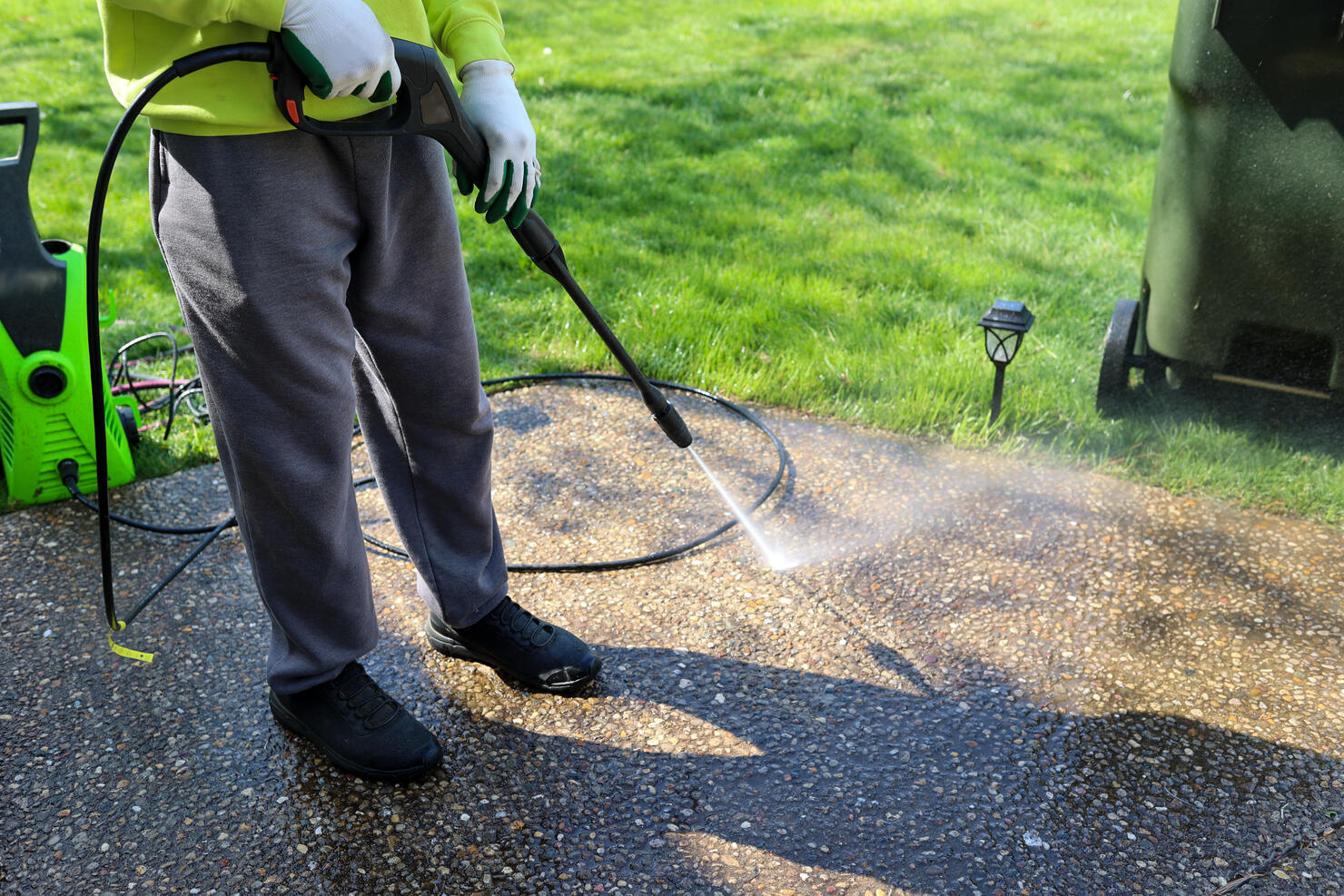 A portrait of a black man power washing a sidewalk