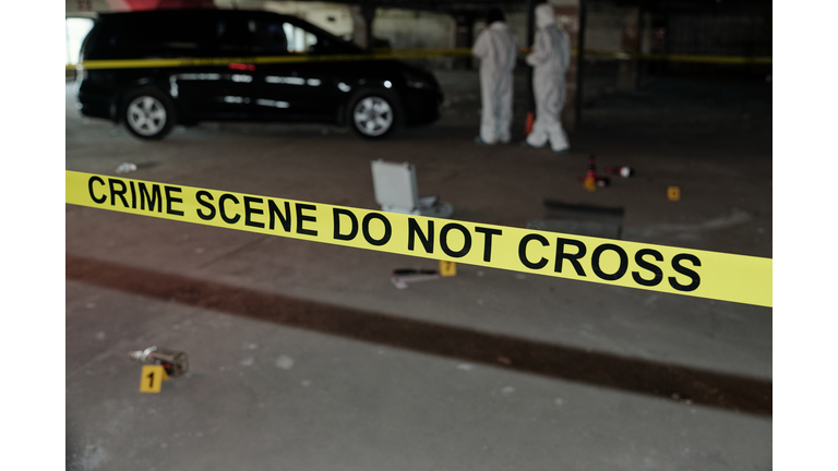 Yellow tape surrounding crime scene in parking area with two experts