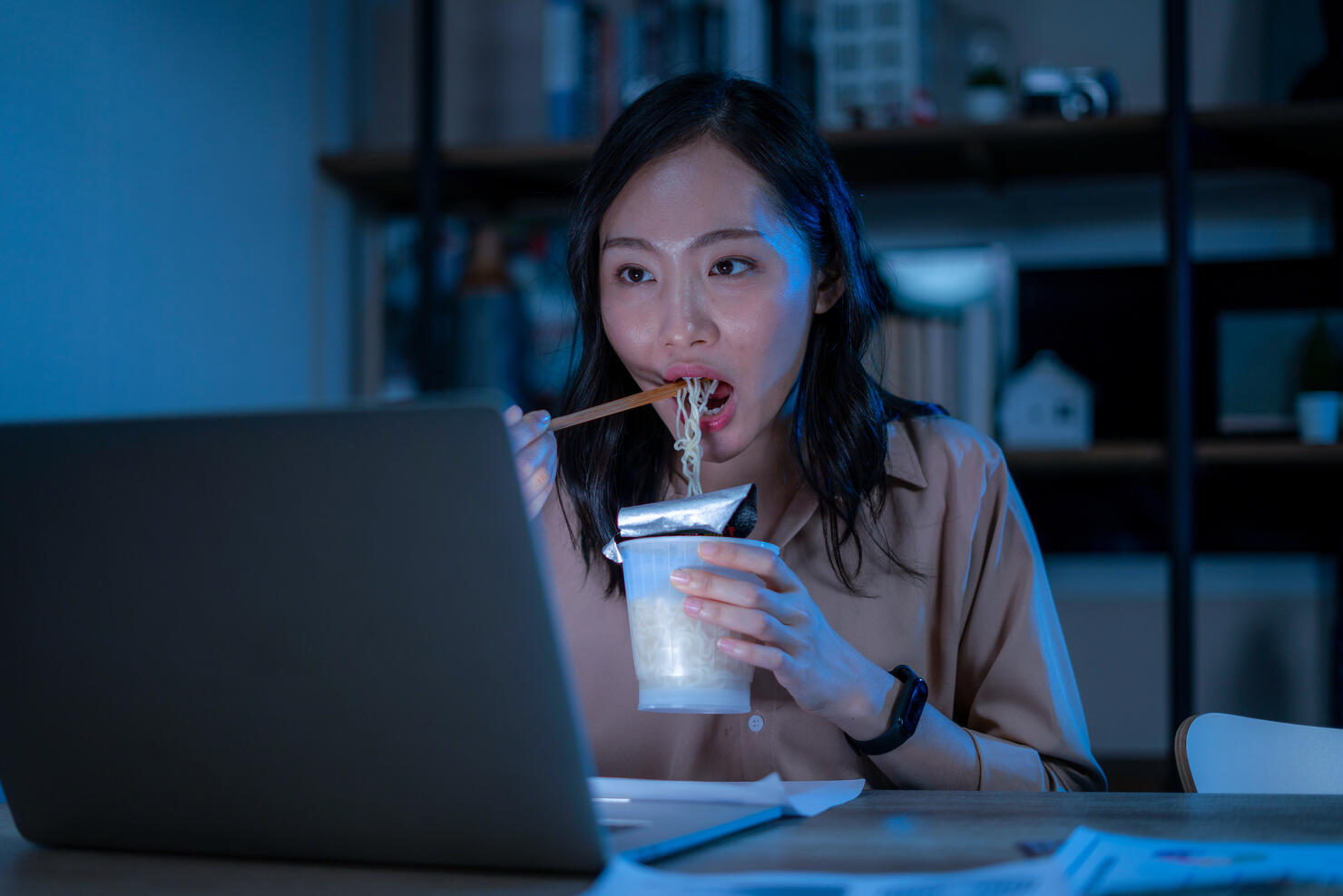 Asia freelance smart business women eating instant noodles while working on laptop in living room at home at night