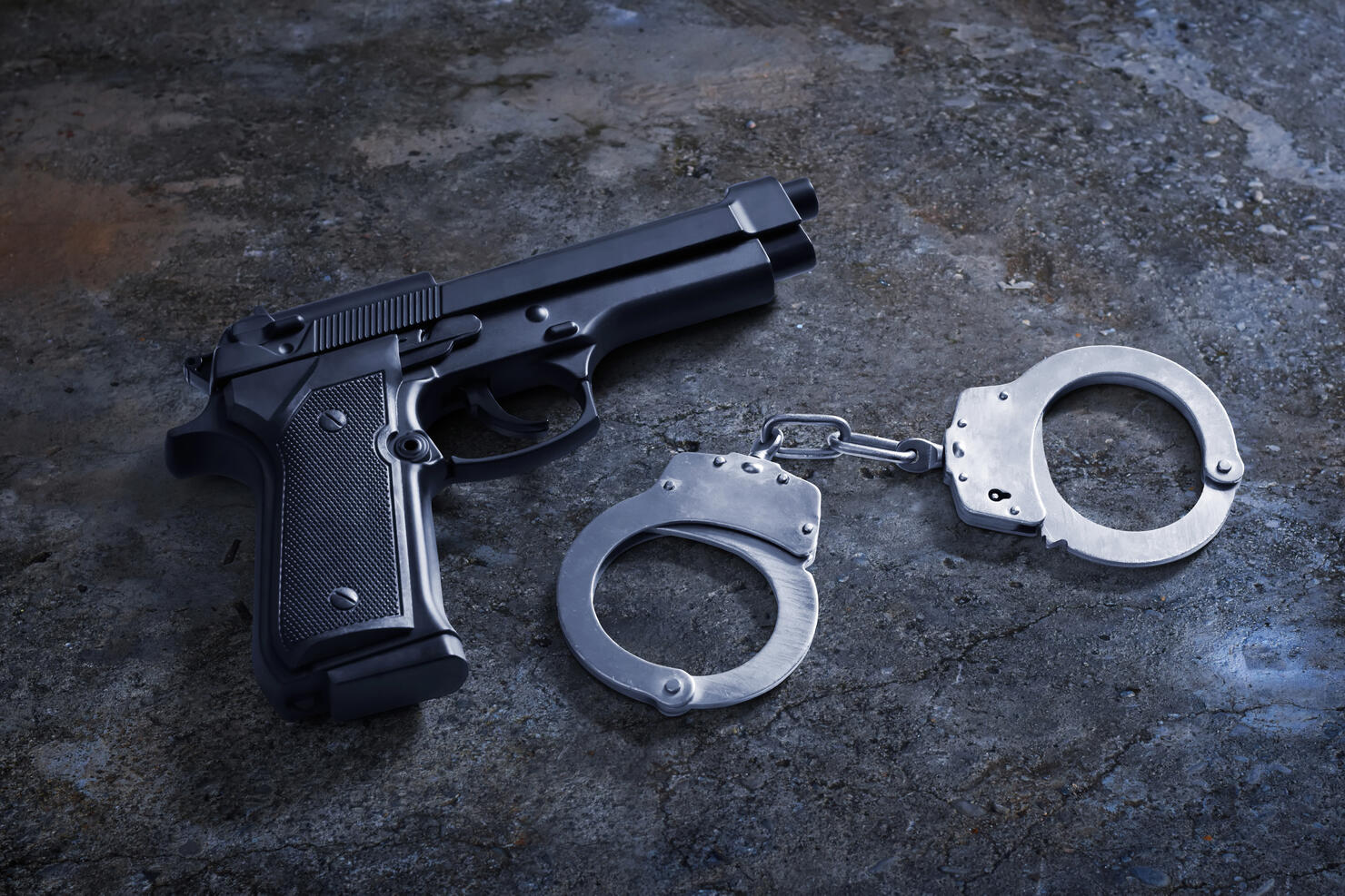 Gun and handcuffs on asphalt ground concrete grunge floor street