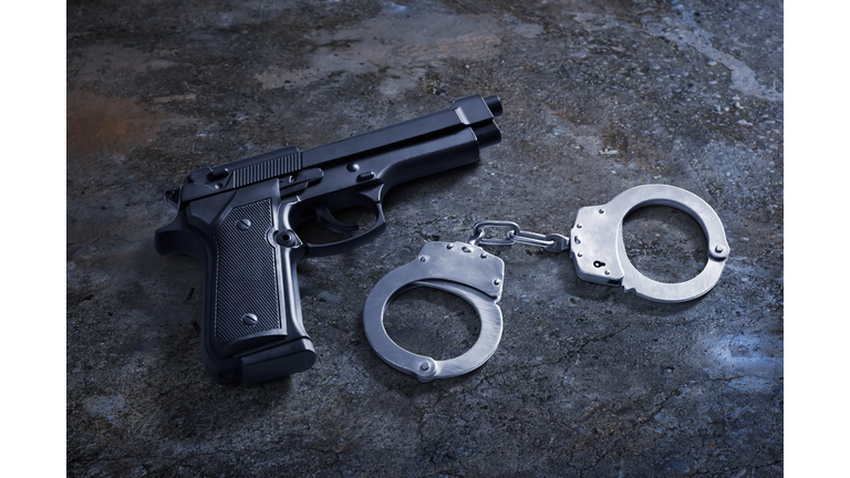 Gun and handcuffs on asphalt ground concrete grunge floor street