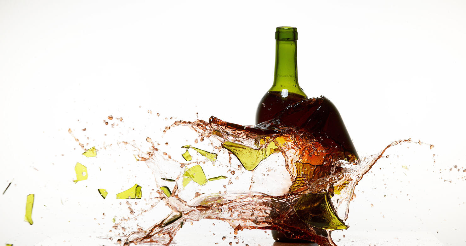 Bottle of Red Wine Breaking and Splashing against White Background