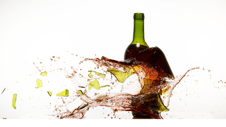 Bottle of Red Wine Breaking and Splashing against White Background