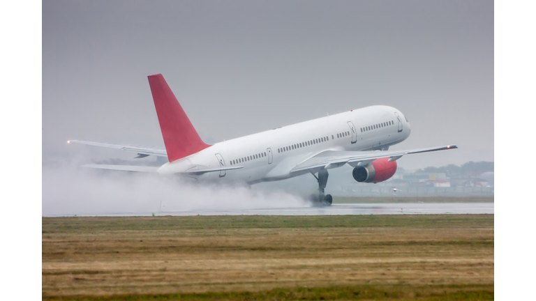 White passenger aircraft moves at the runway in heavy rain