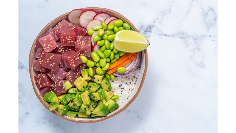 Tuna Poke bowl on white marble with Edamame, avocado and radish.