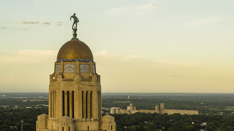 Nebraska State Capitol topped with finial and thunderbird mosaics, stands tall in Downtown Lincoln, NE, under morning sky