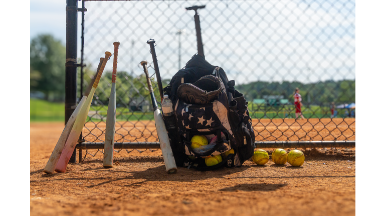 Girls' Softball Team Equipment and Players in the Background