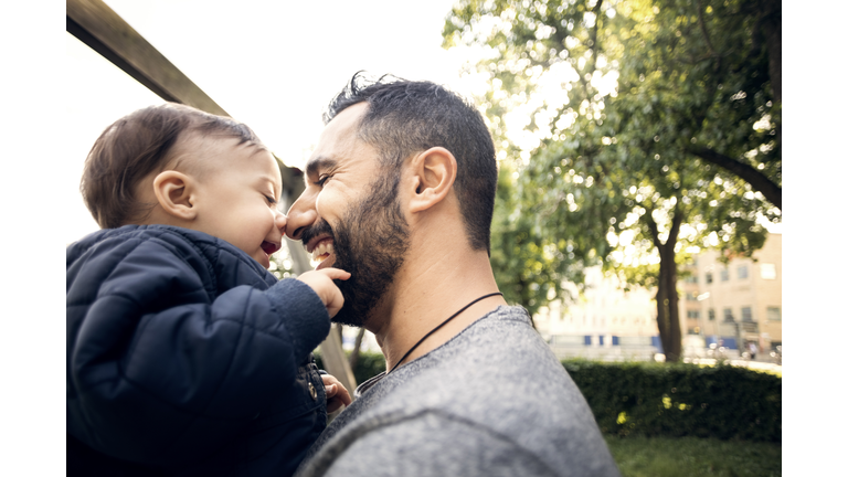 Close-up of smiling father carrying toddler at park