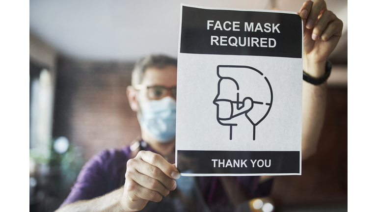 Business owner setting up face mask required sign in cafe window