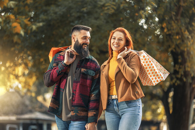 Happy couple with shopping bags in autumn park