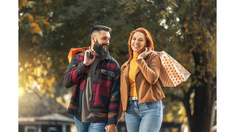 Happy couple with shopping bags in autumn park