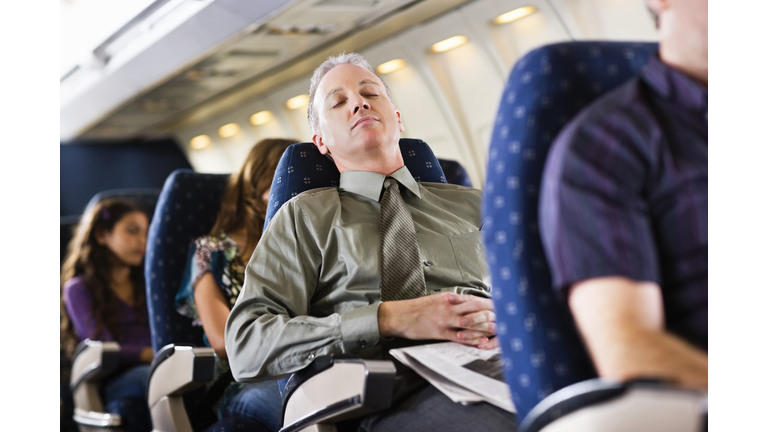 business man sleeping on airplane