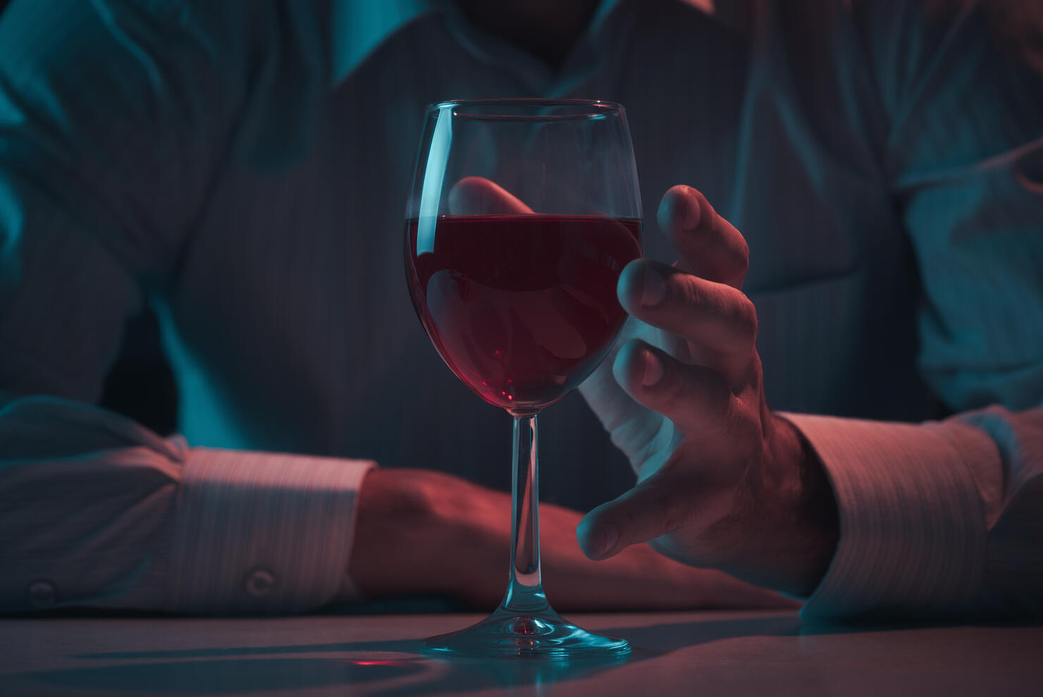Hand reaches for a glass of alcohol