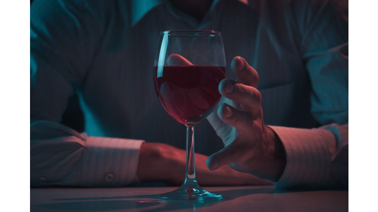 Hand reaches for a glass of alcohol