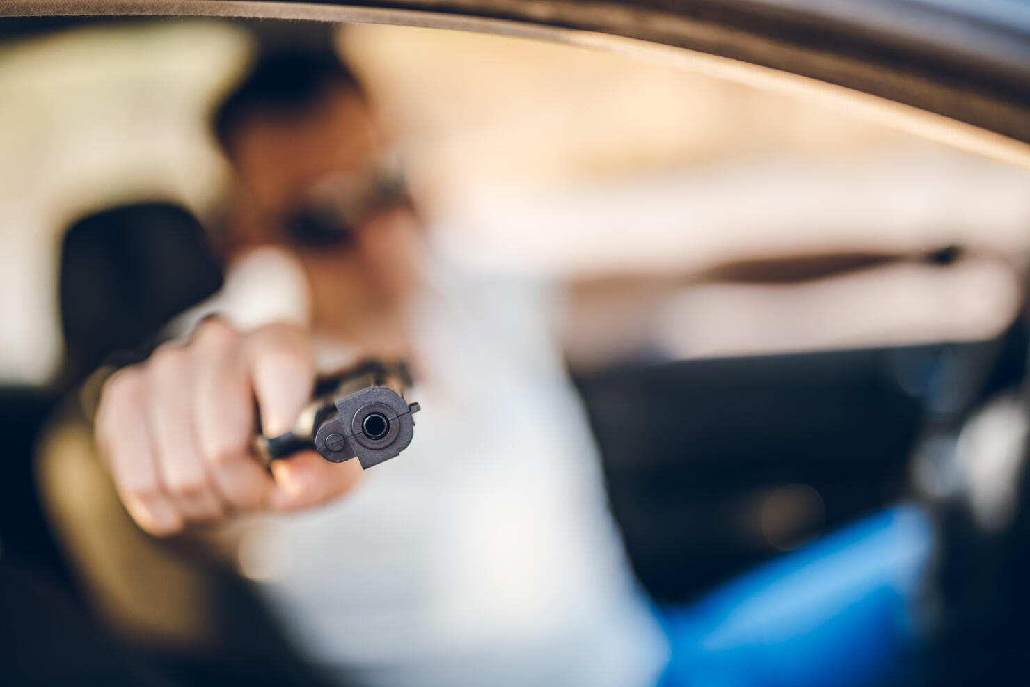 Man driving a car and holding a gun