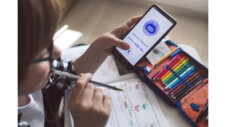 Smiling boy using system AI Chatbot on mobile application. Chatbot conversation, Ai Artificial Intelligence technology. Futuristic technology. Virtual assistant on internet.