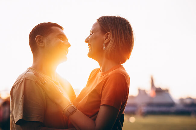 Couple in love shares a warm embrace at sunset, with the golden light creating a romantic and intimate atmosphere.