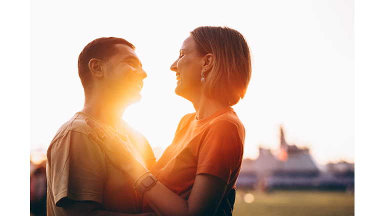 Couple in love shares a warm embrace at sunset, with the golden light creating a romantic and intimate atmosphere.