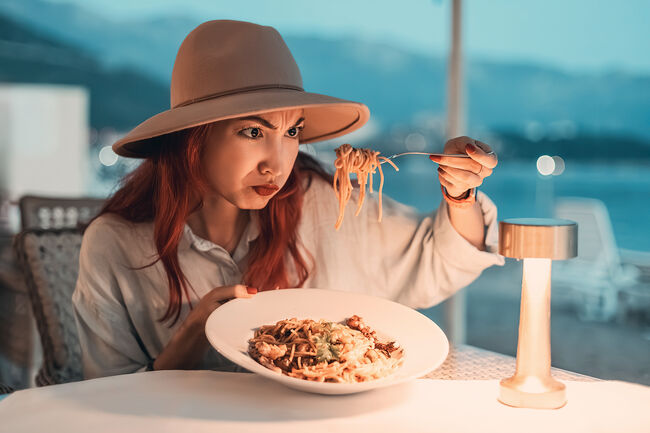 Woman disgusted by her spaghetti while dining in restaurant by the sea