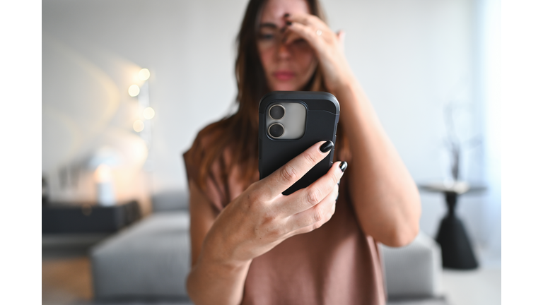 Woman feeling stressed, having headache from phone overuse
