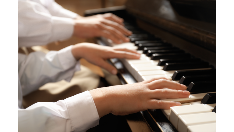 Young woman with child playing piano, closeup. Music lesson