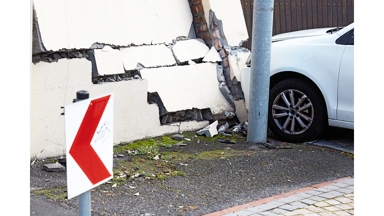 Smashed wall and damaged car in the aftermath of a traffic accident