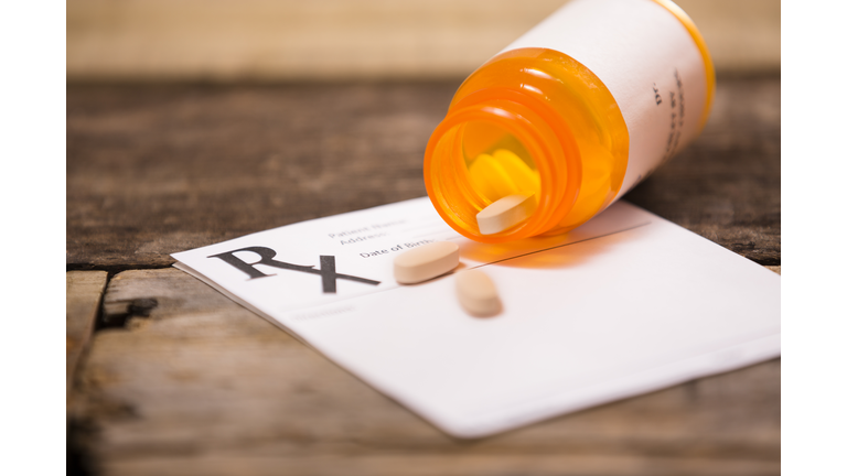 Pharmacy medication bottle with prescription pad. Pills spilling out.
