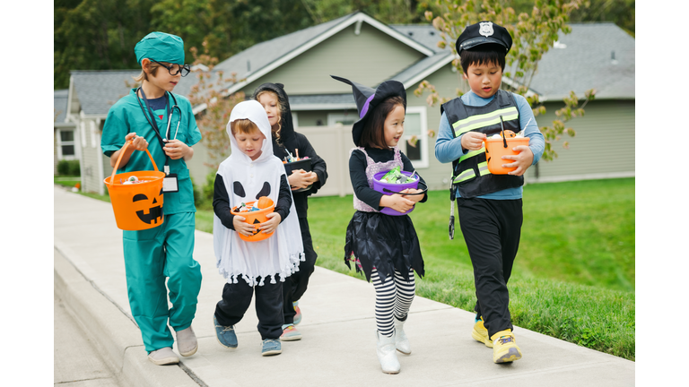 Children Trick Or Treat For Halloween In Residential Neighborhood