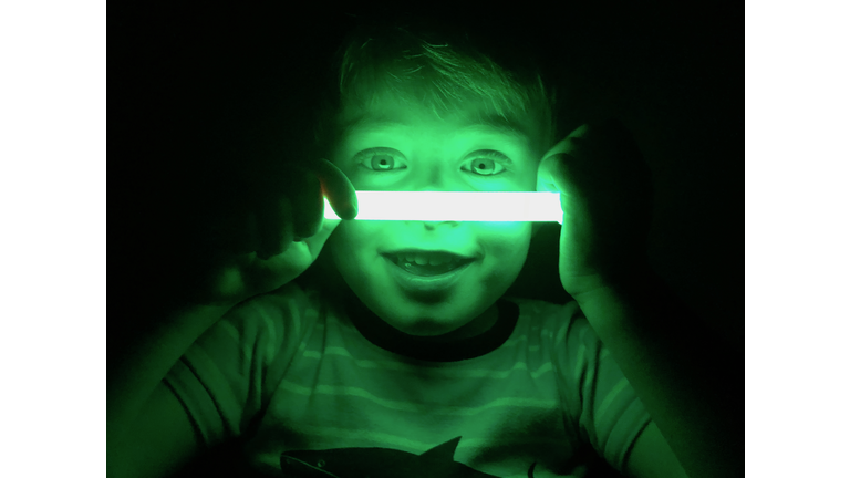 Smiling boy with glow stick, dark background