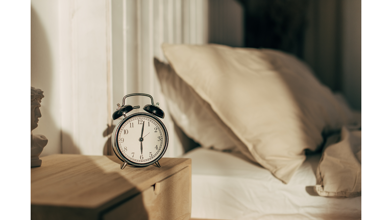 Hand of woman turning off alarm clock on night table