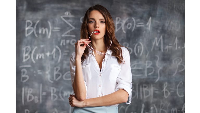 smart sexy female teacher in eyeglasses near blackboard