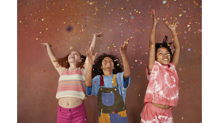 Cheerful kids enjoying together under falling confetti
