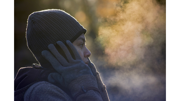 Close-up of woman exhaling breath vapor at park during winter